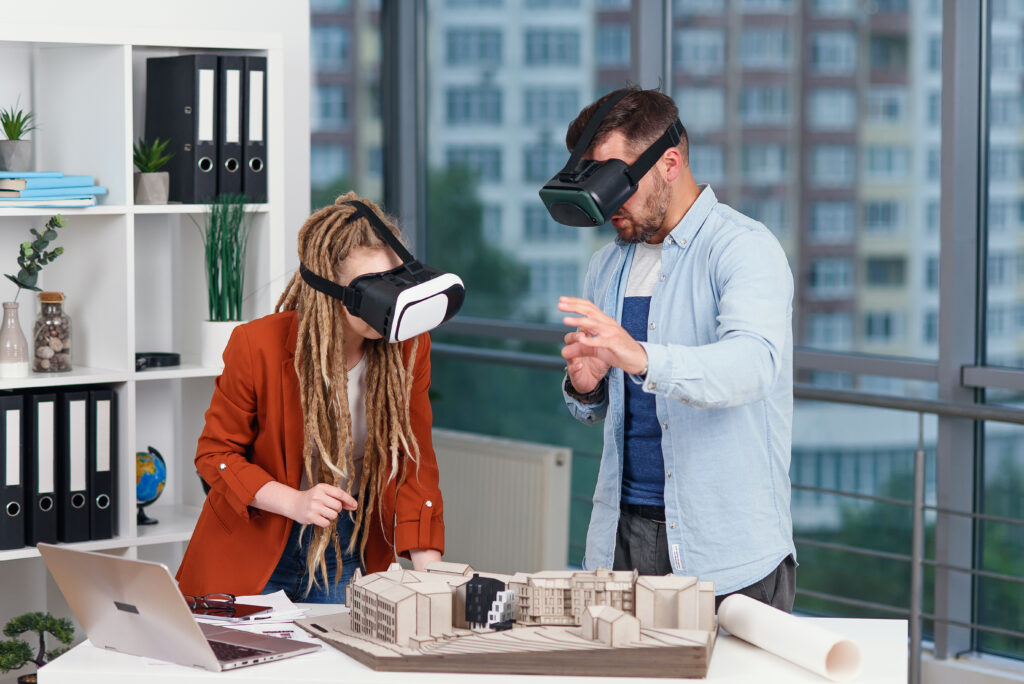 Couple of designers analyse mock-up of future house using augmented reality glasses in modern office