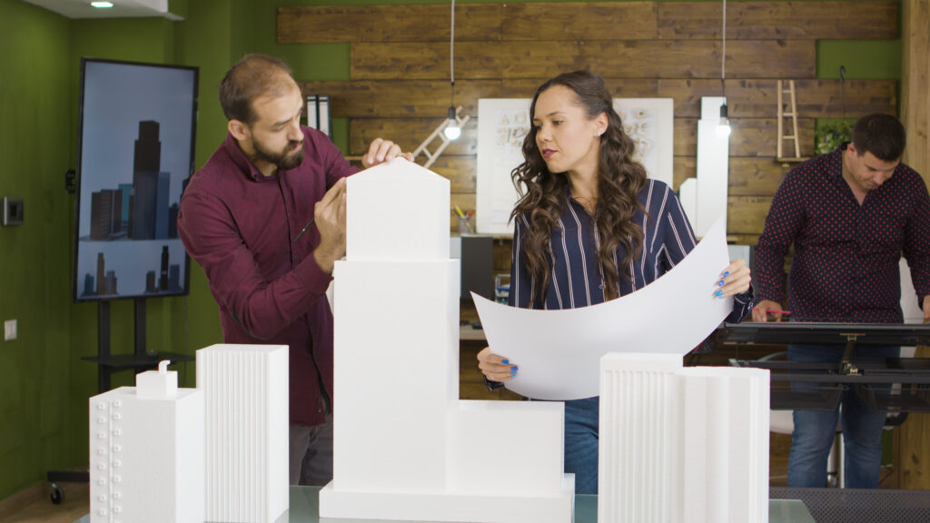 Group of architects working on 3D printed models of buildings